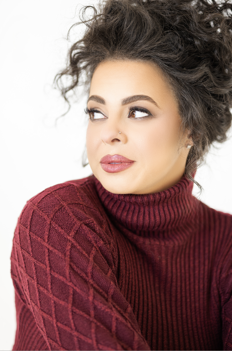 Woman sitting in quiet reflection, looking to the side with a thoughtful expression, representing the emotional weight and hope of the holiday season.