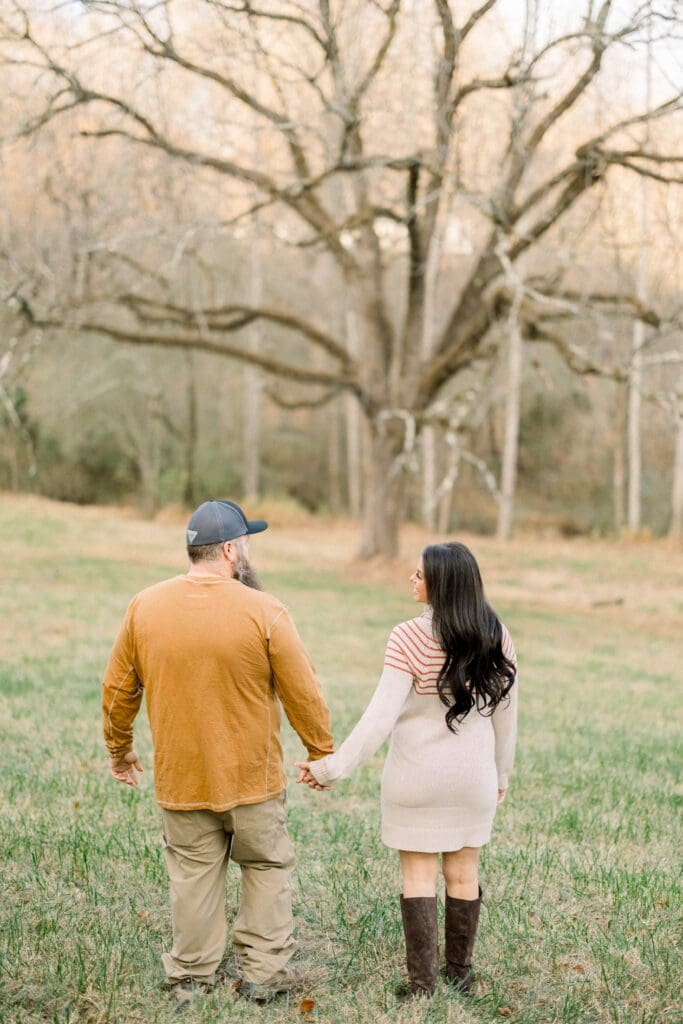 Couple walking hand in hand through an open field, representing commitment, perseverance, and enduring love through life’s seasons